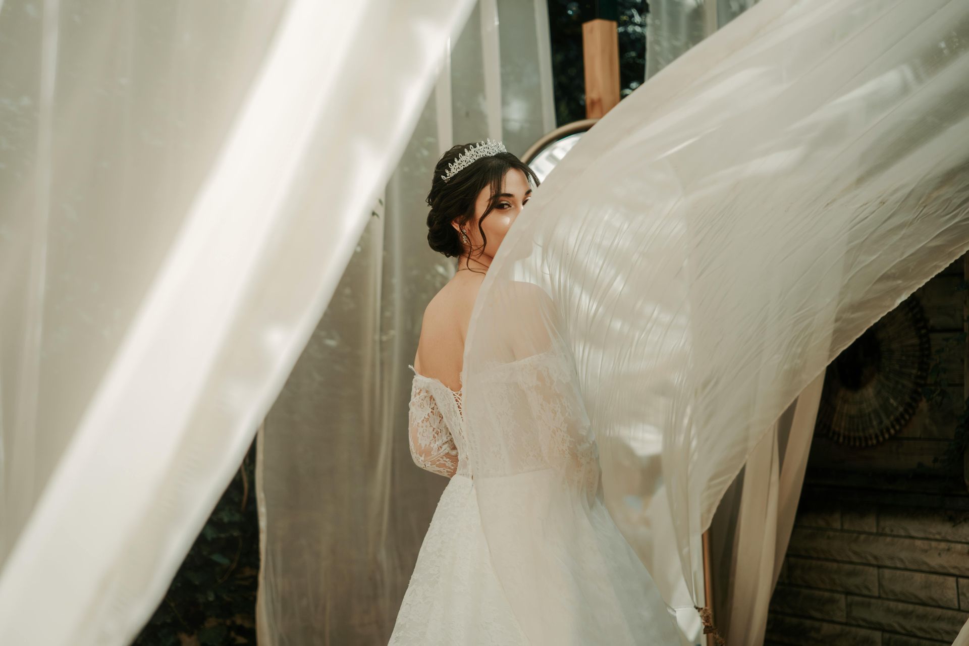 A bride in a wedding dress is sitting on the ground holding a bouquet of flowers.