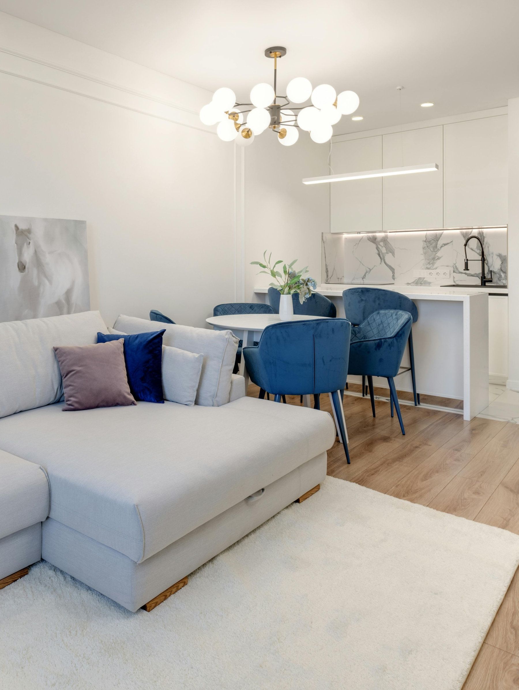 A living room with a white couch and blue chairs