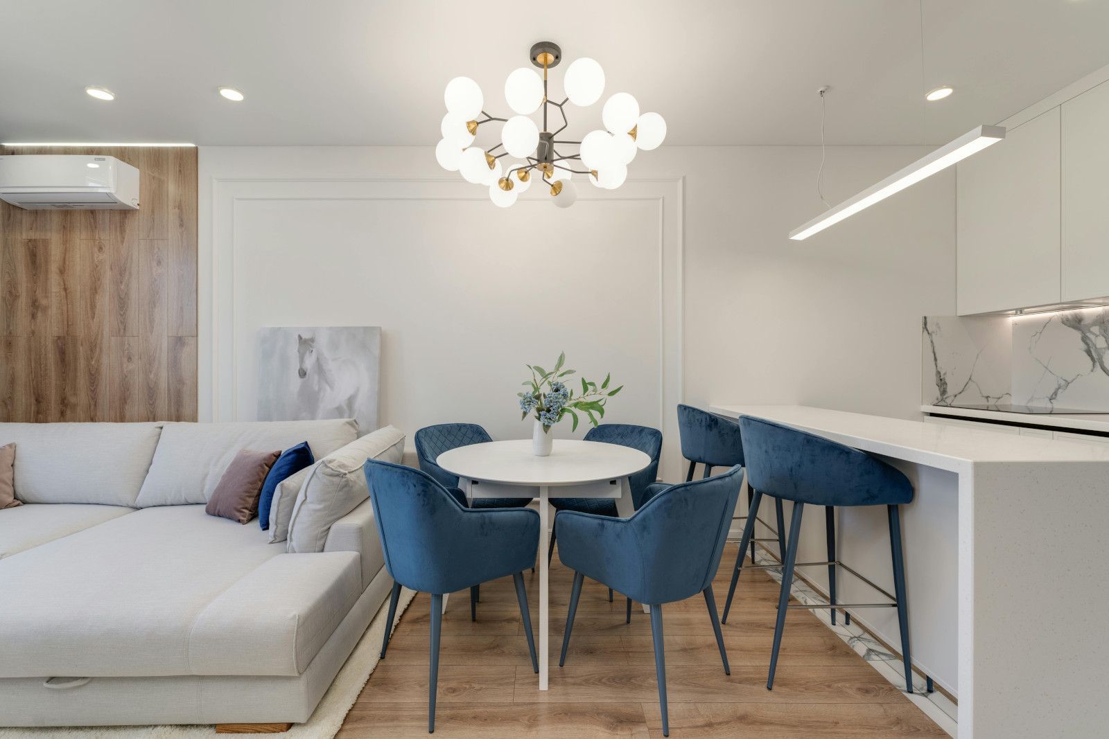 A living room with a dining table and chairs and a chandelier.