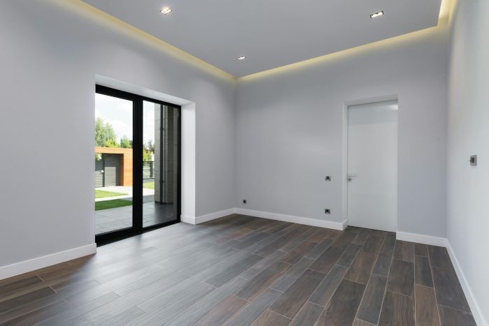 An empty room with hardwood floors and sliding glass doors.