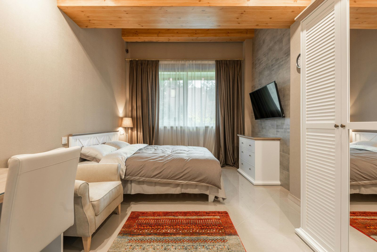 A bedroom with a bed , chair , dresser and television.