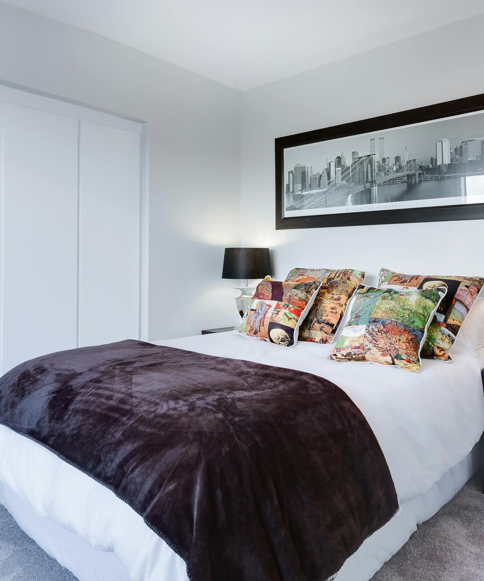 A bedroom with a large picture on the wall above the bed