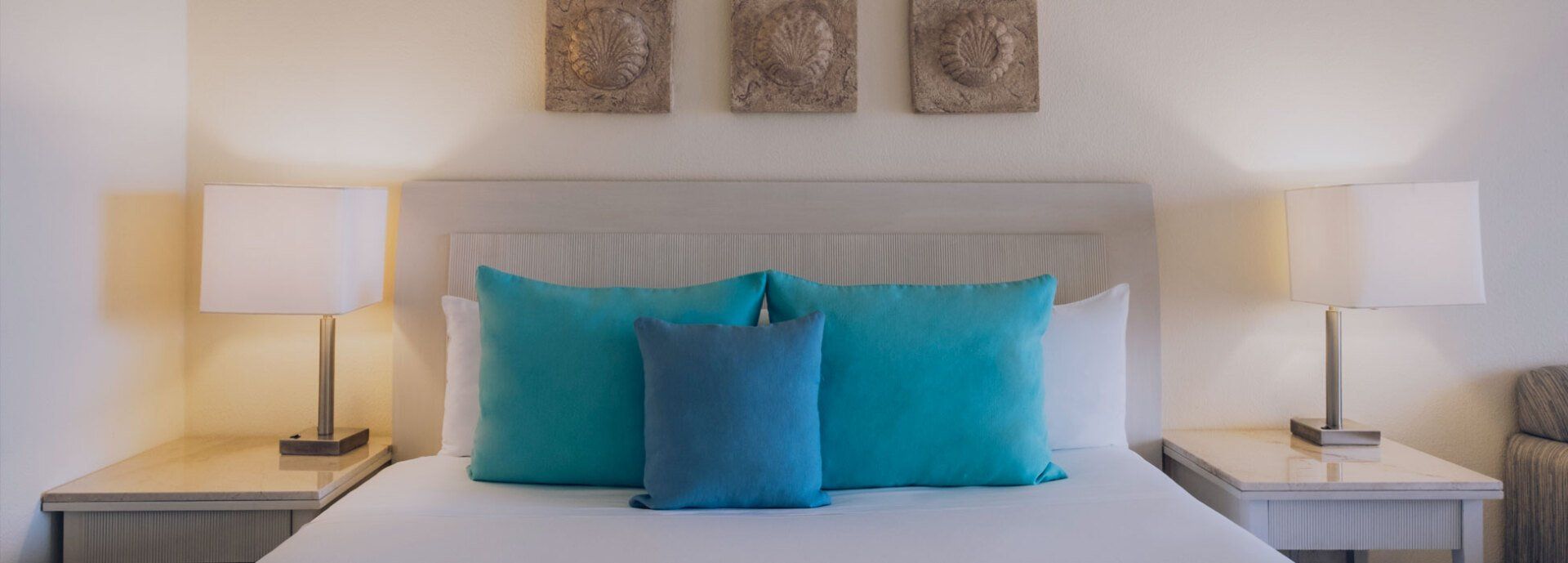 Una cama con almohadas azules y lámparas en una habitación de hotel.