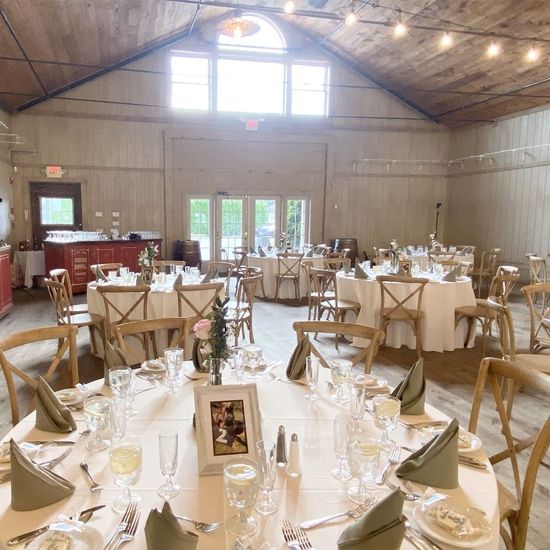 A large room with tables and chairs set up for a wedding reception