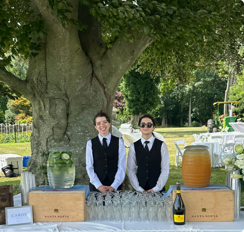 Two people standing behind a table with glasses and a bottle of champagne