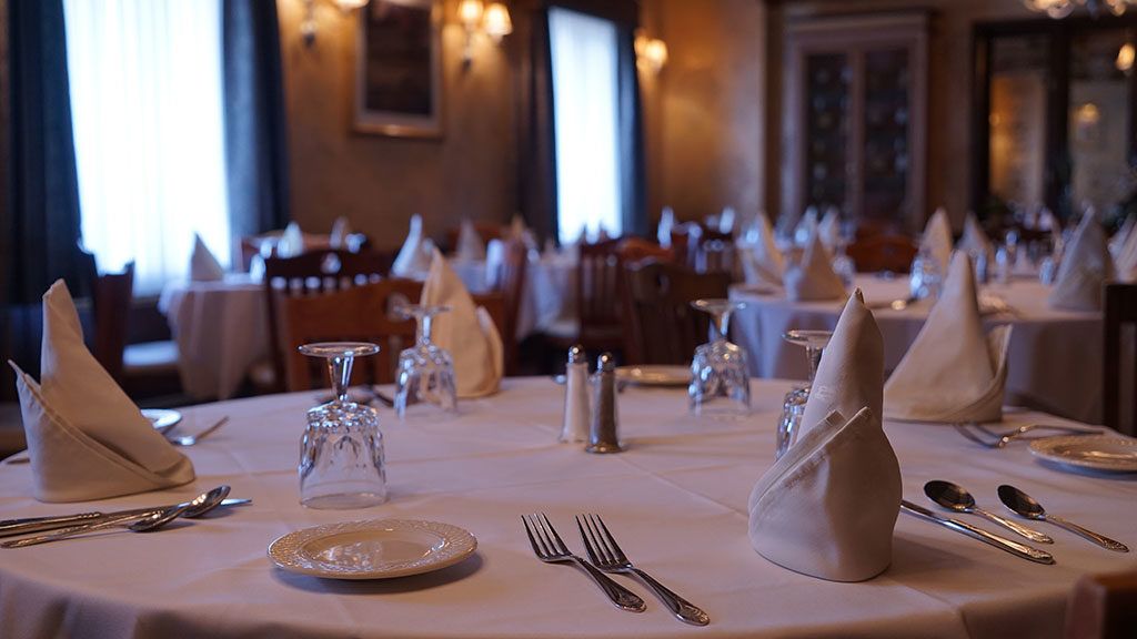 A table in a restaurant with plates , glasses , silverware and napkins on it.