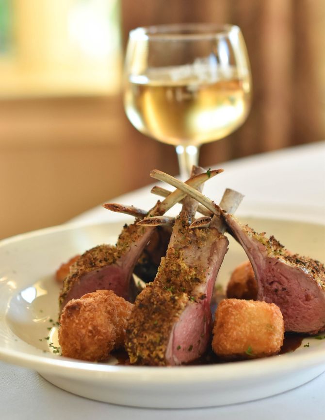 A plate of food with a glass of wine in the background