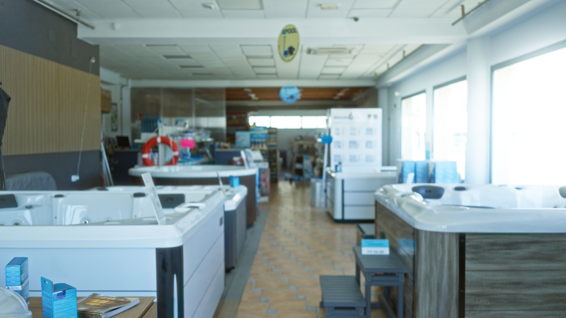Spacious showroom displaying hot tubs and spa units arranged in rows under bright lighting.