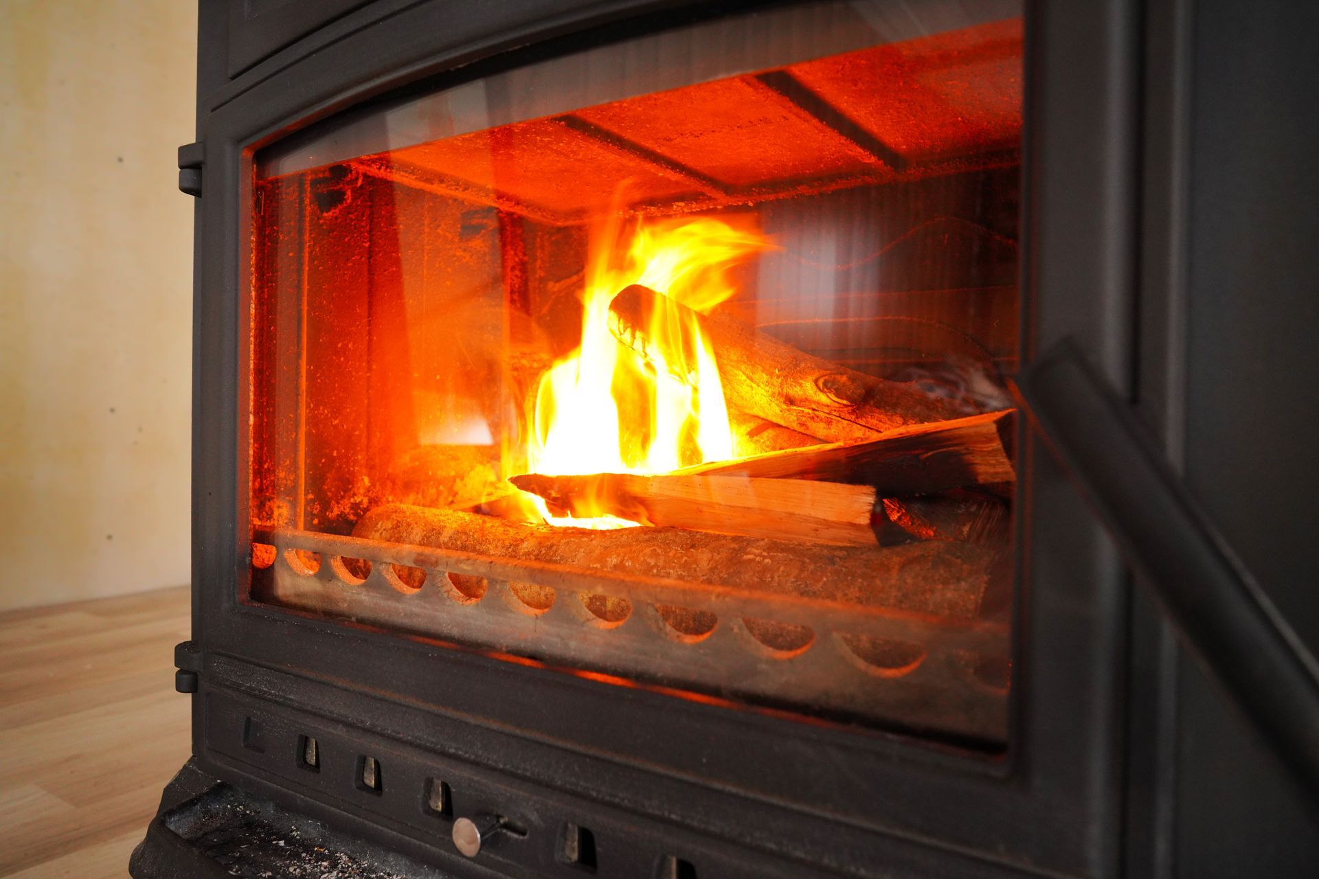 Wood-burning stove with burning logs visible through glass, flames glowing brightly inside.