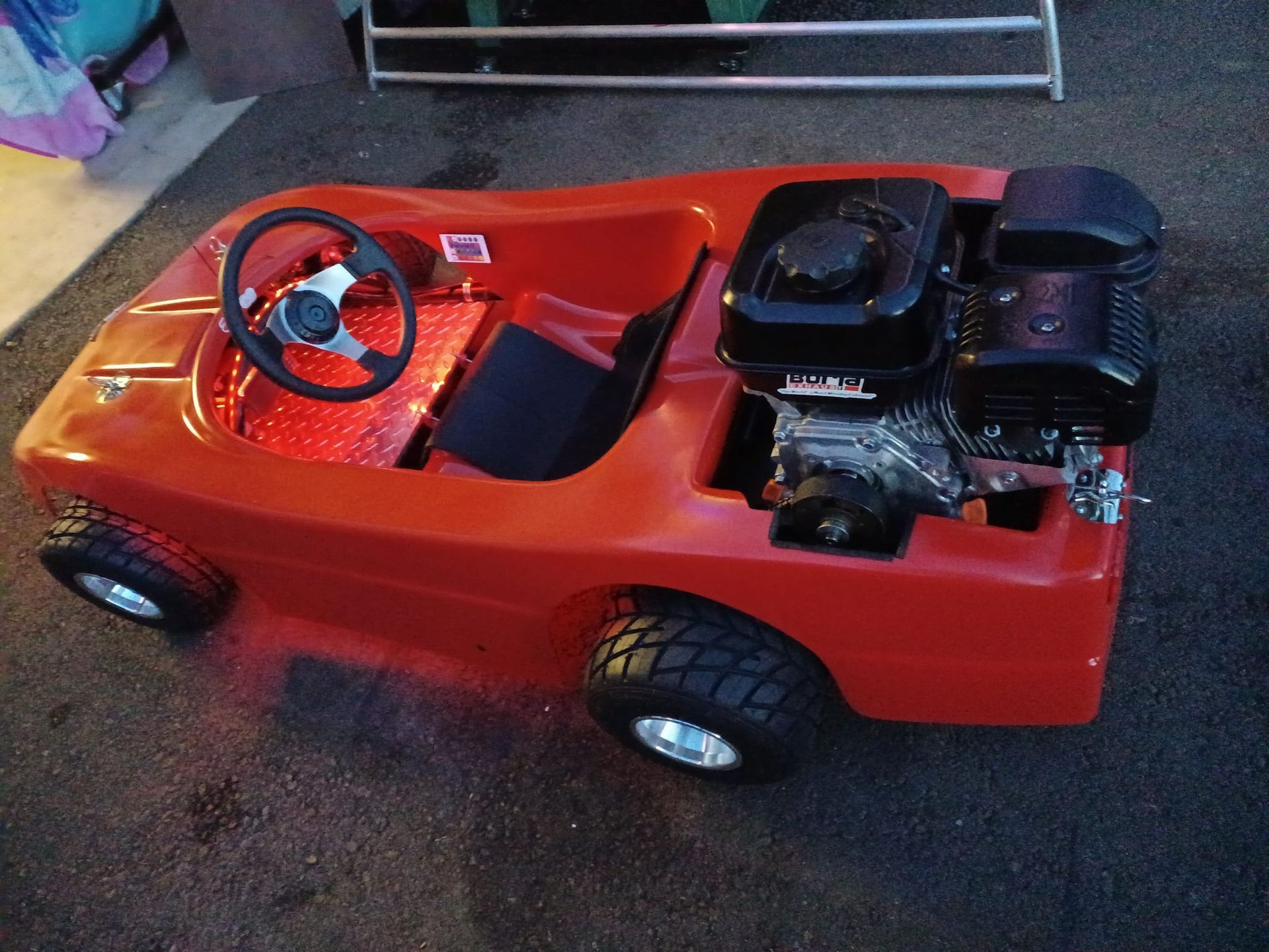 A red toy car with a steering wheel and engine