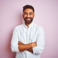 A man with a beard is standing with his arms crossed and smiling.