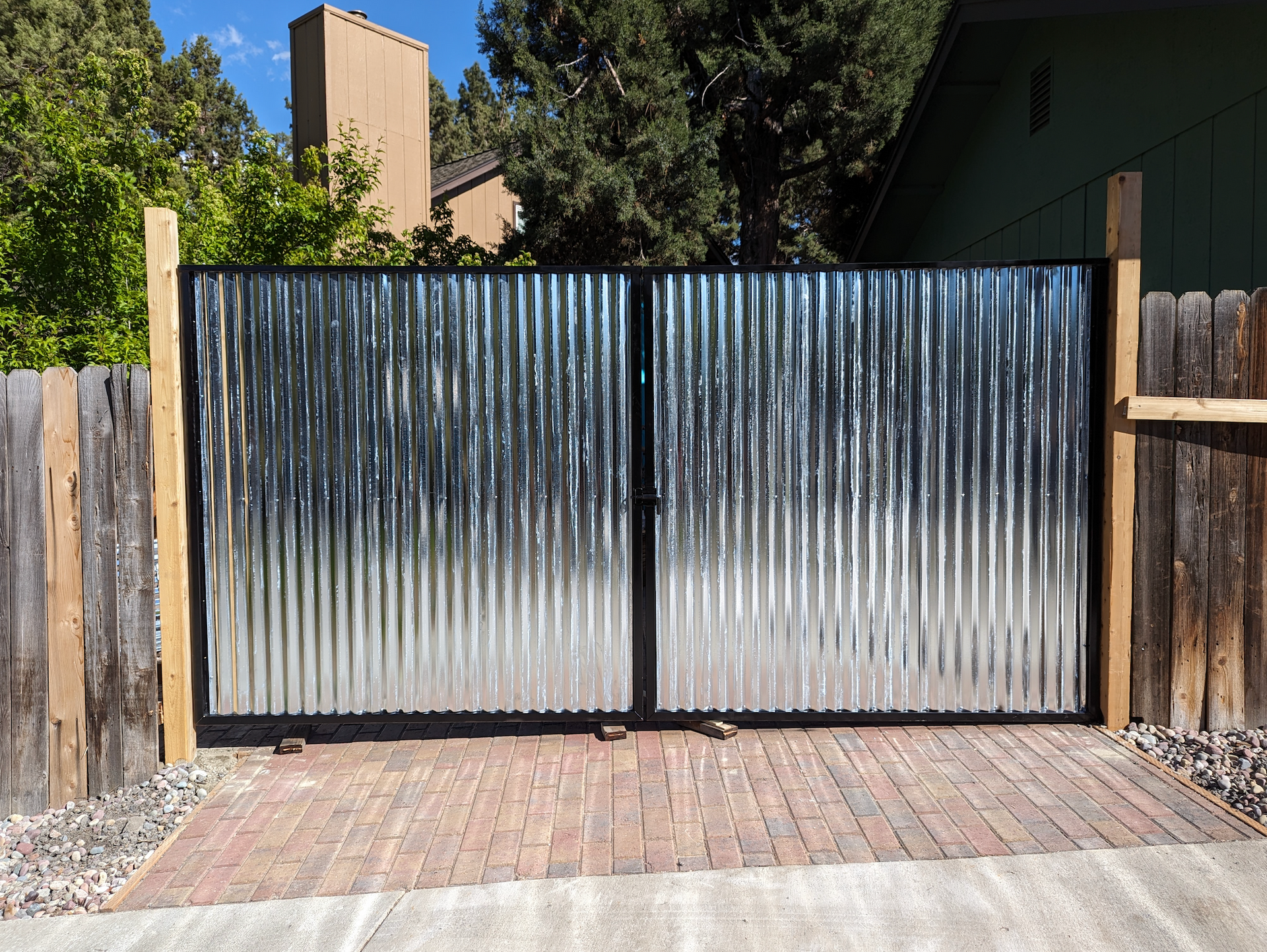 A metal gate with a wooden fence behind it