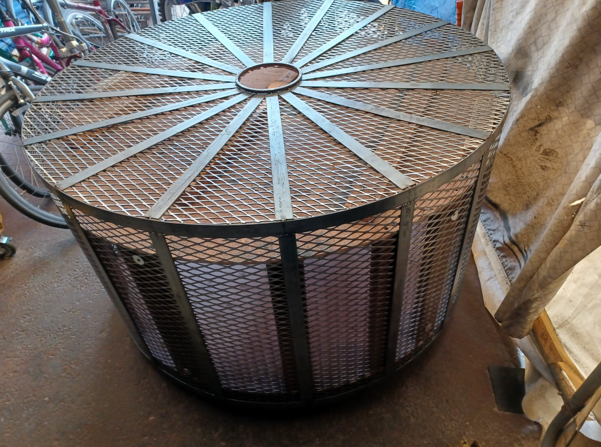 A round metal cage with a bicycle in the background