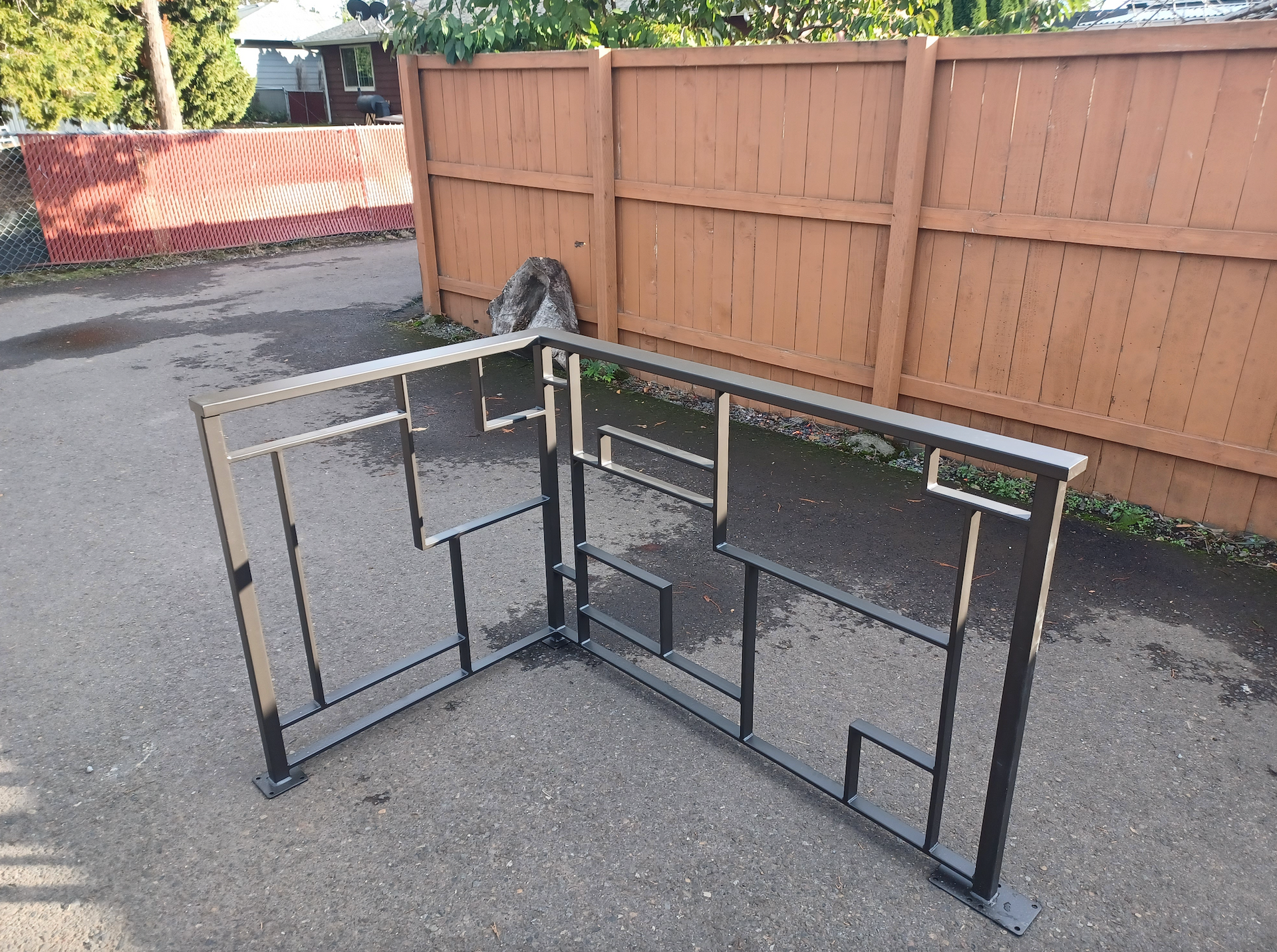 A piece of metal is sitting on the ground in front of a wooden fence.