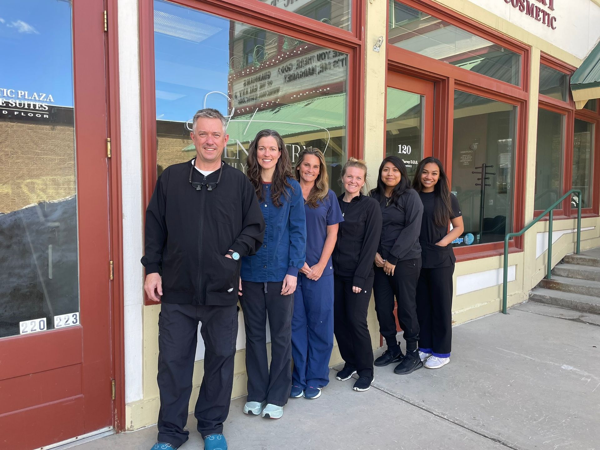 Dental office staff standing outside storefront.