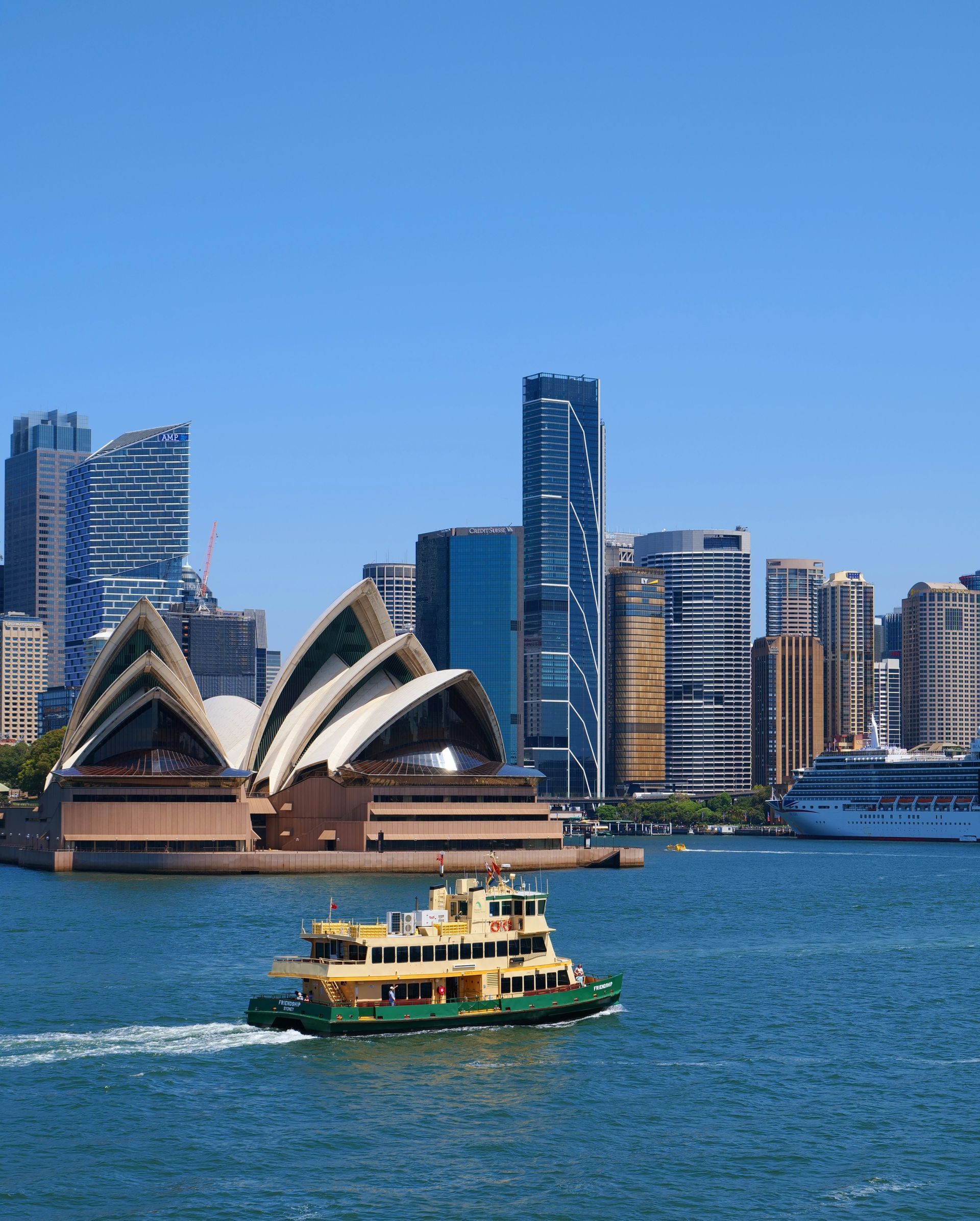 Colorful buildings line a river against a backdrop of mountains under a clear blue sky.