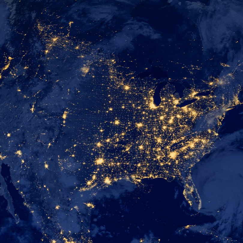 Nighttime satellite view of the United States, illuminated by city lights against a dark blue background.