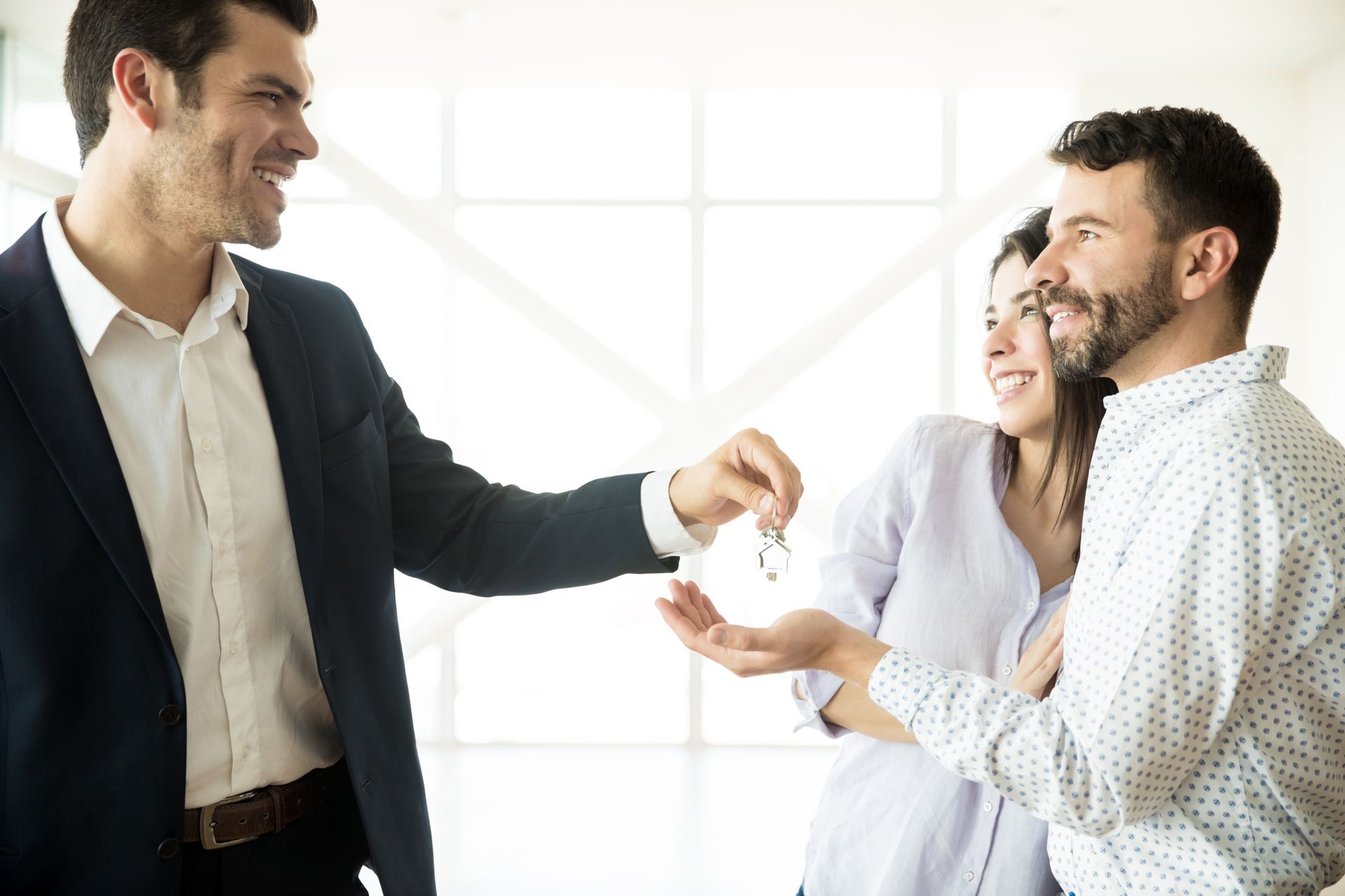 Three coworkers smiling and shaking hands in a bright office