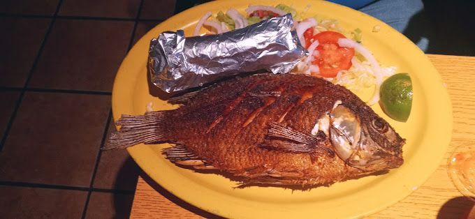 A yellow plate topped with a fish and a baked potato