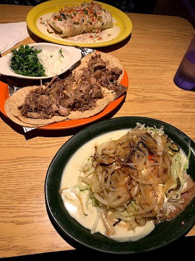 Three plates of food are sitting on a wooden table