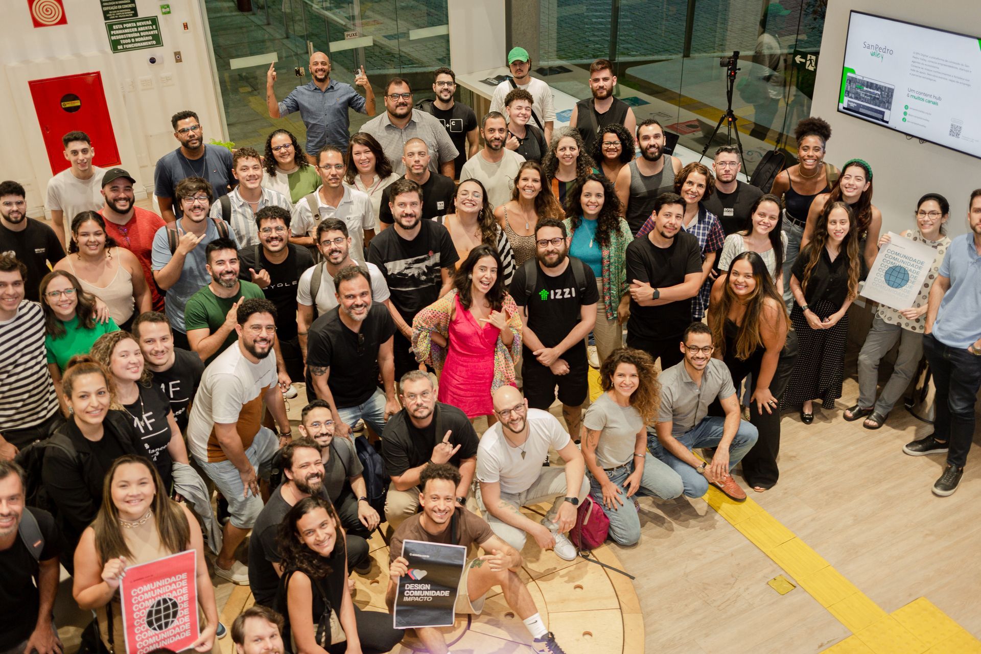 Um grande grupo de pessoas está posando para uma foto em uma sala.