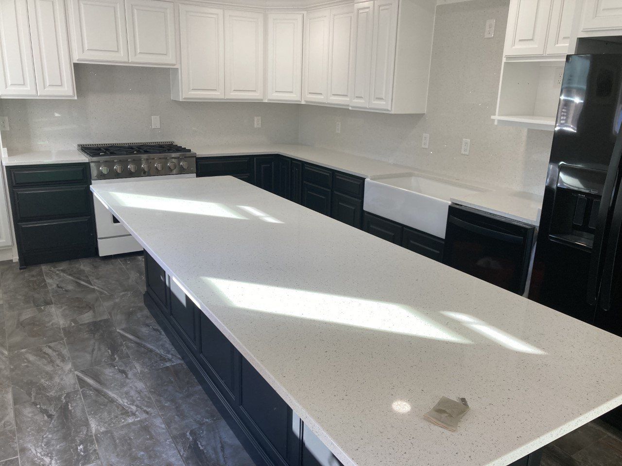 A kitchen with black cabinets and white counter tops - Luther Falls Kitchen & Bath - Champaign, IL