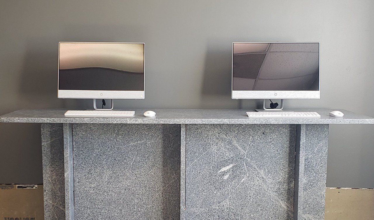 Two computer monitors are sitting on a marble counter- Luther Falls Kitchen & Bath - Champaign, IL