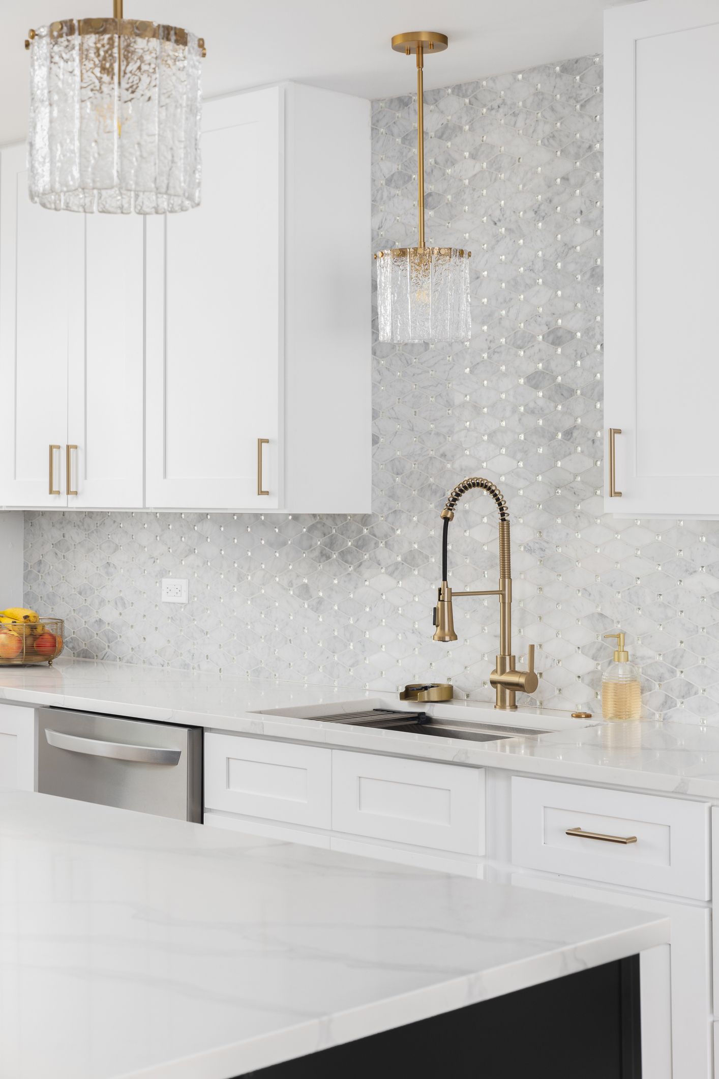 A gold kitchen faucet detail with white cabinets. A gold kitchen faucet detail with white cabinets.