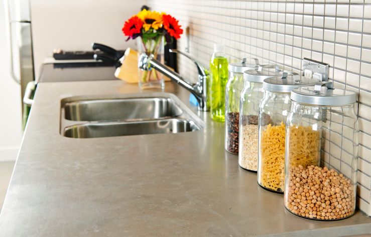 Modern small kitchen interior with glass jars on soapstone countertop.