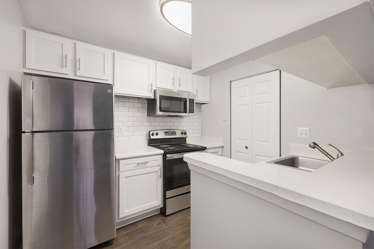 Stainless steel kitchen appliances in a modern, bright white kitchen.