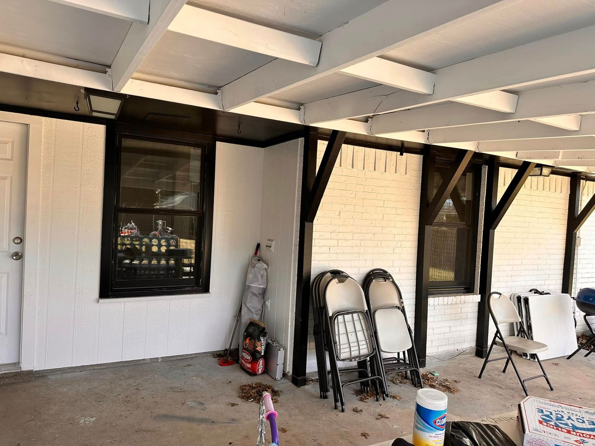 A covered porch with folding chairs and a window