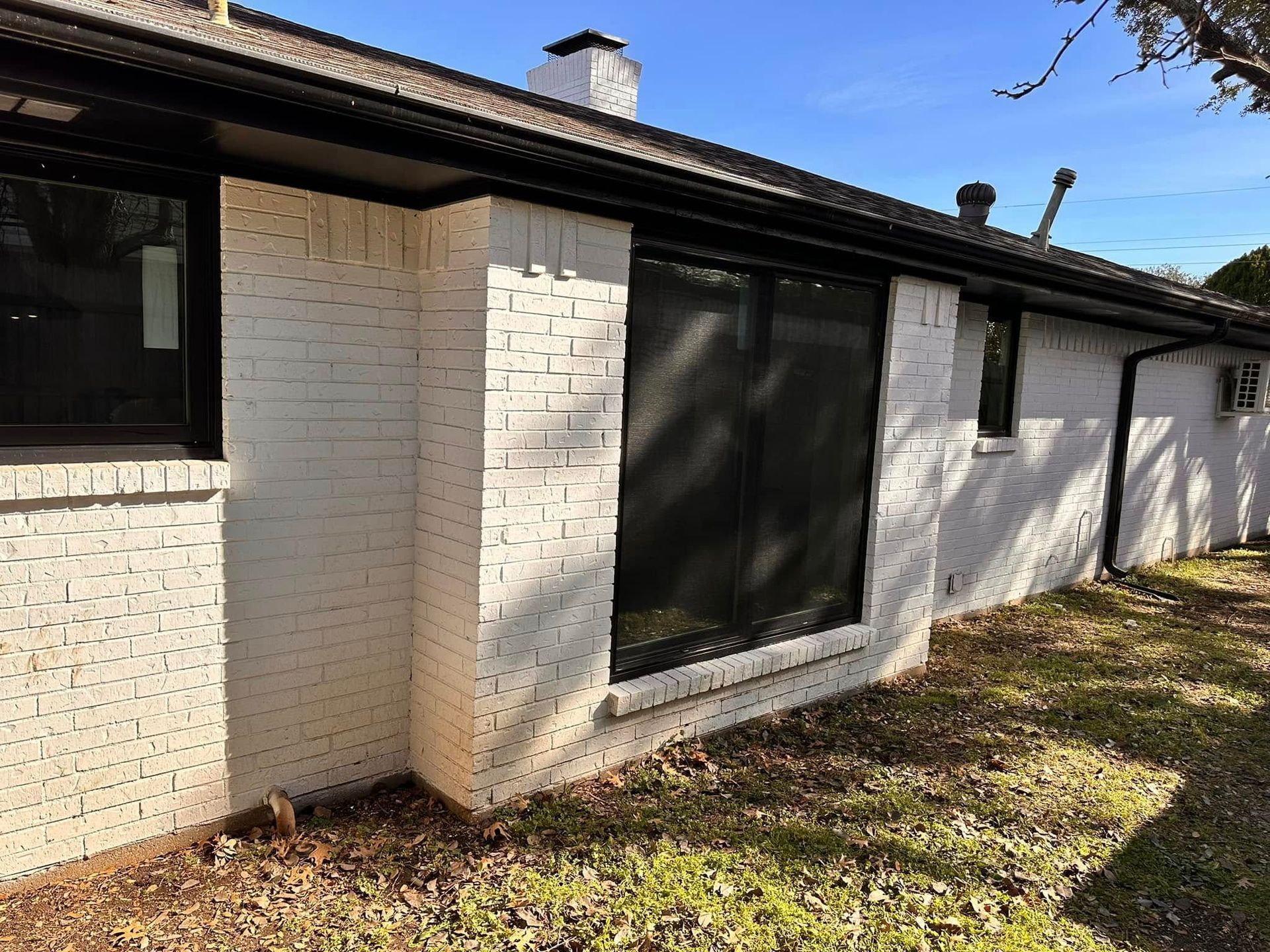 A white brick house with black windows and a black roof