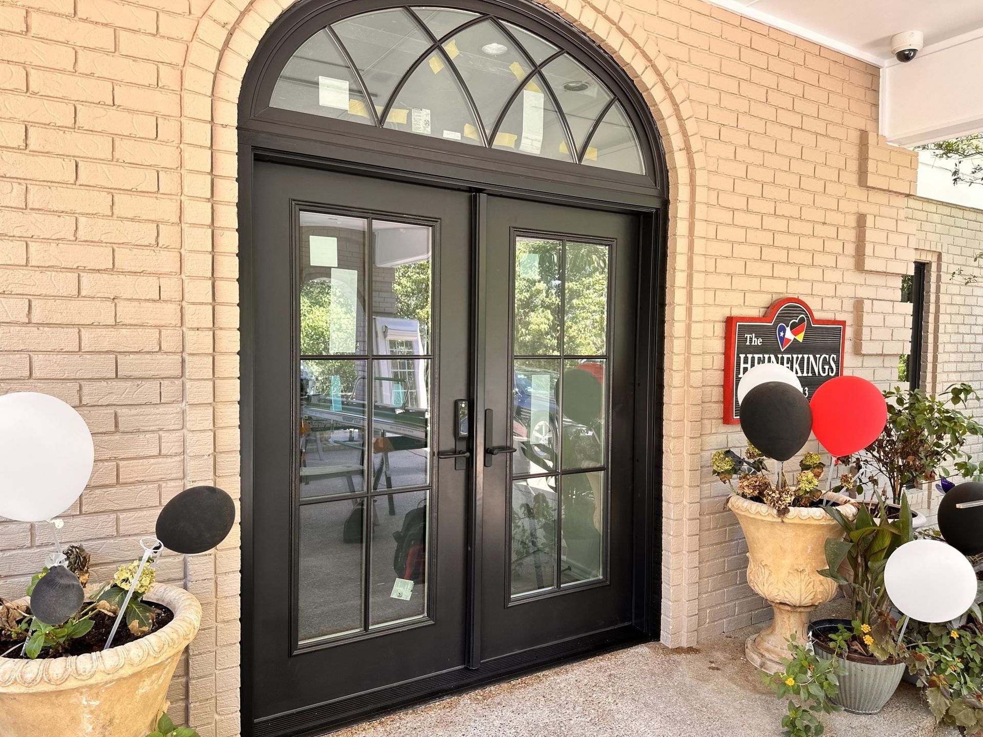 A brick building with a black door and potted plants in front of it.