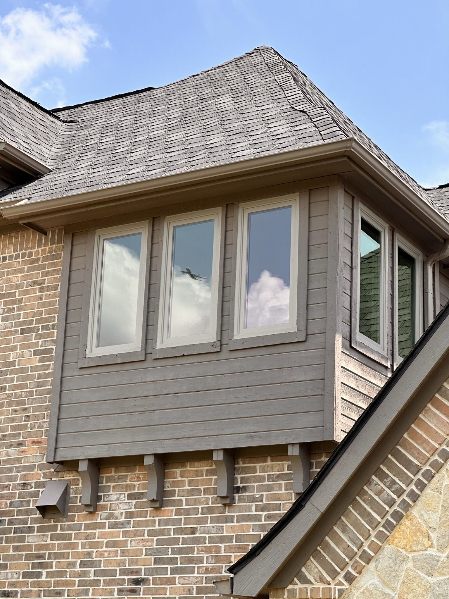 A brick house with a bay window on the side of it.