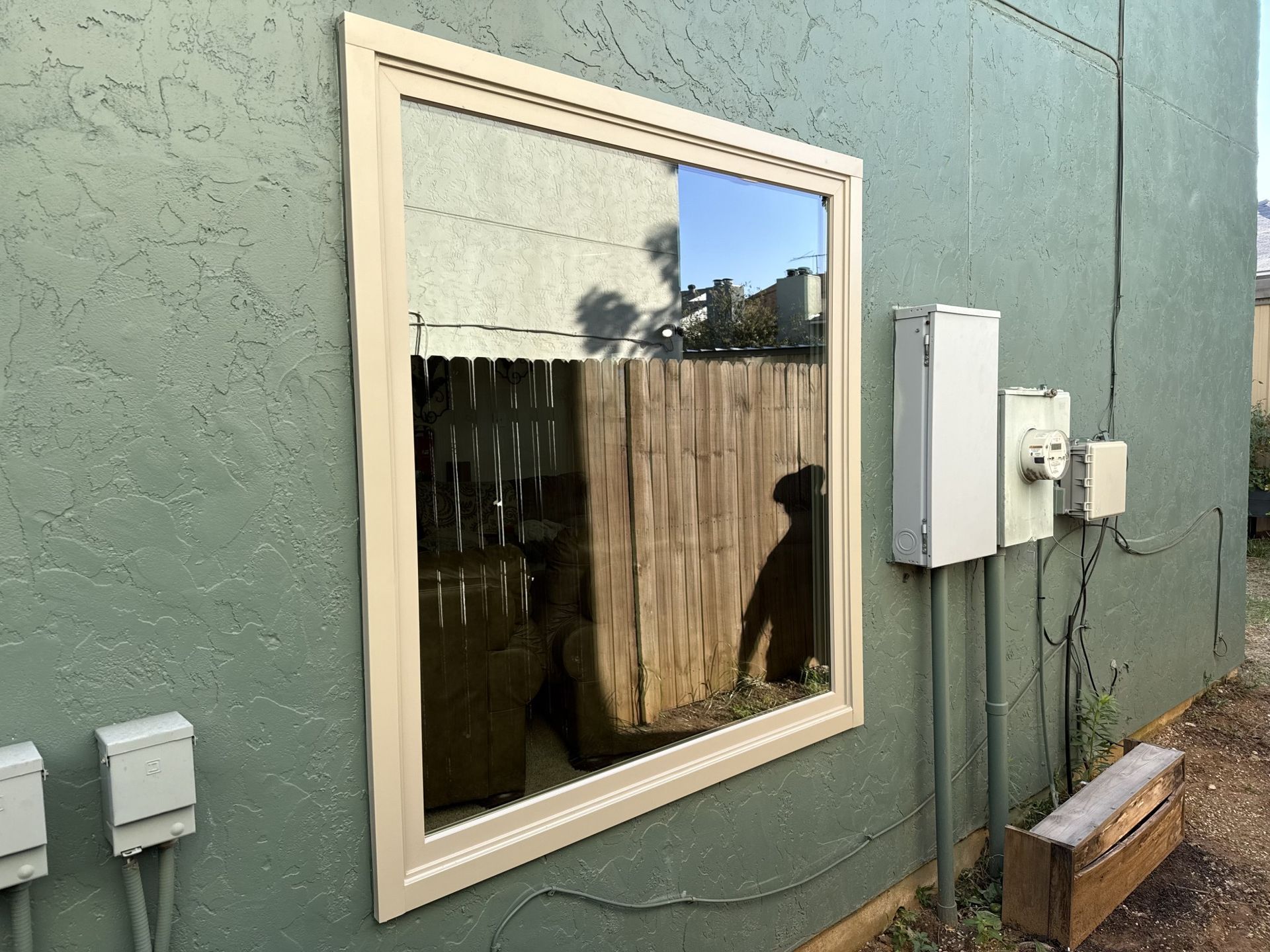A large window on the side of a building with a reflection of a fence.