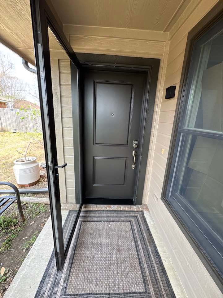 A black door is sitting on a porch next to a window.