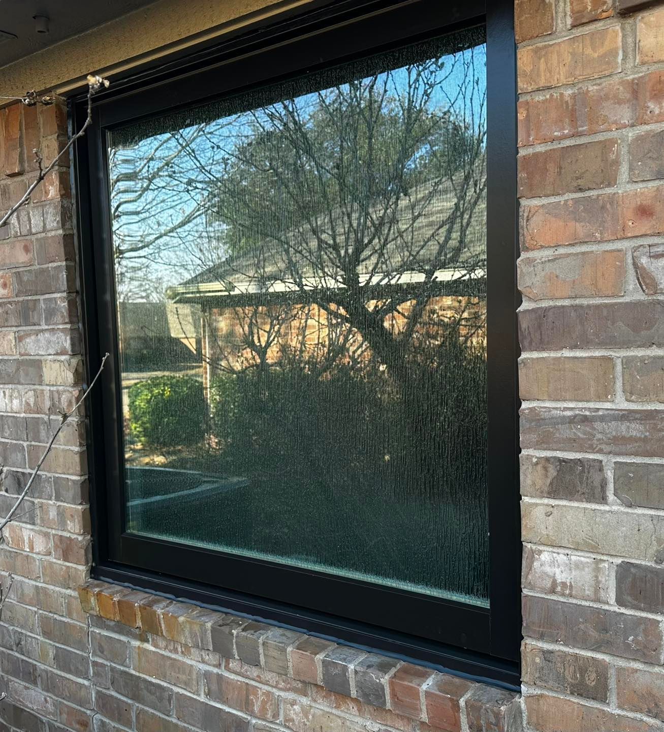 A large window on a brick wall with a black frame.
