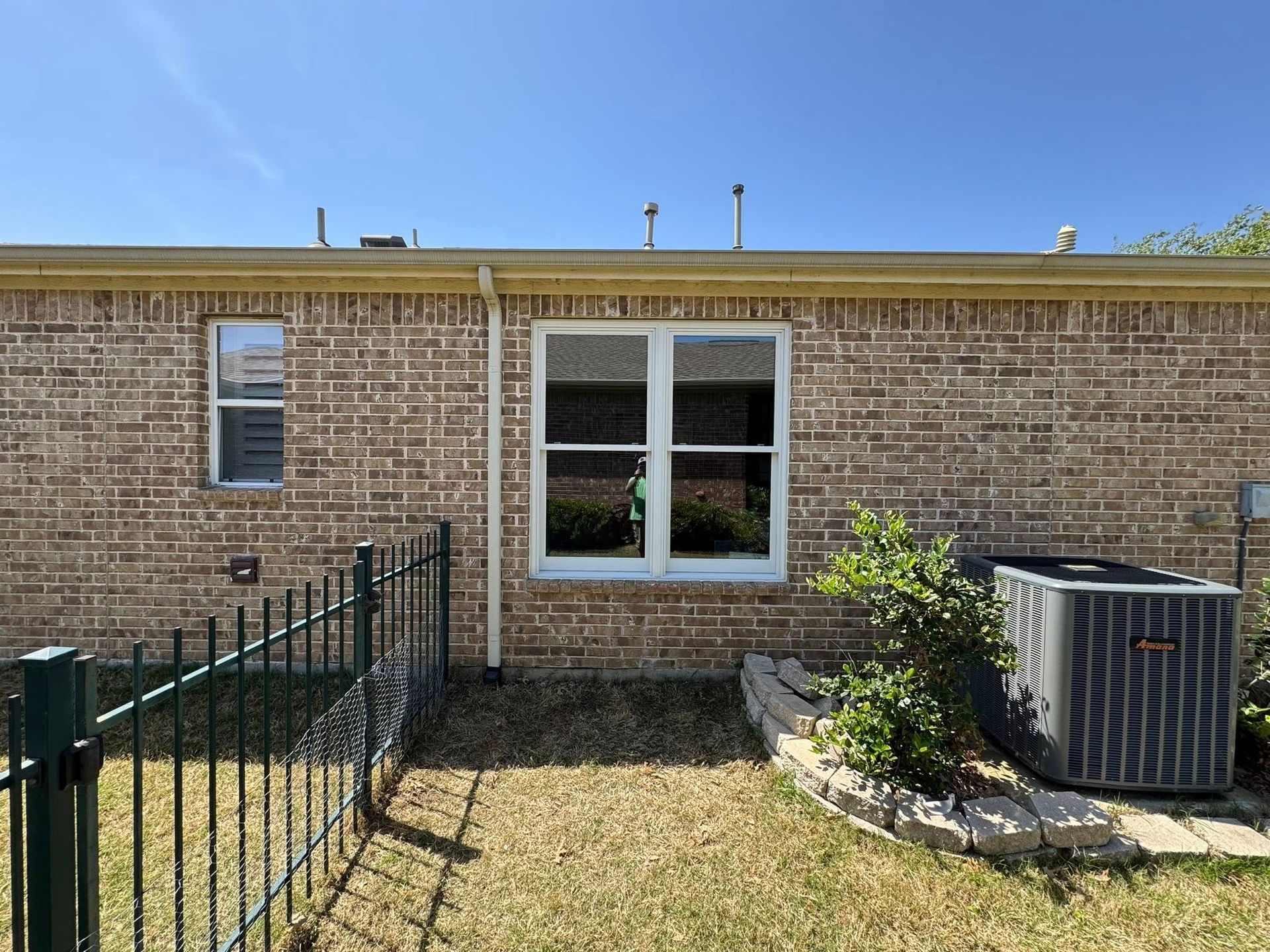 The back of a brick house with a fence and a window.