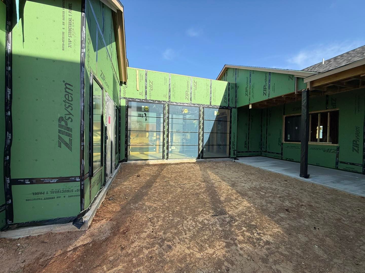 A house is being built with green siding and a lot of windows.