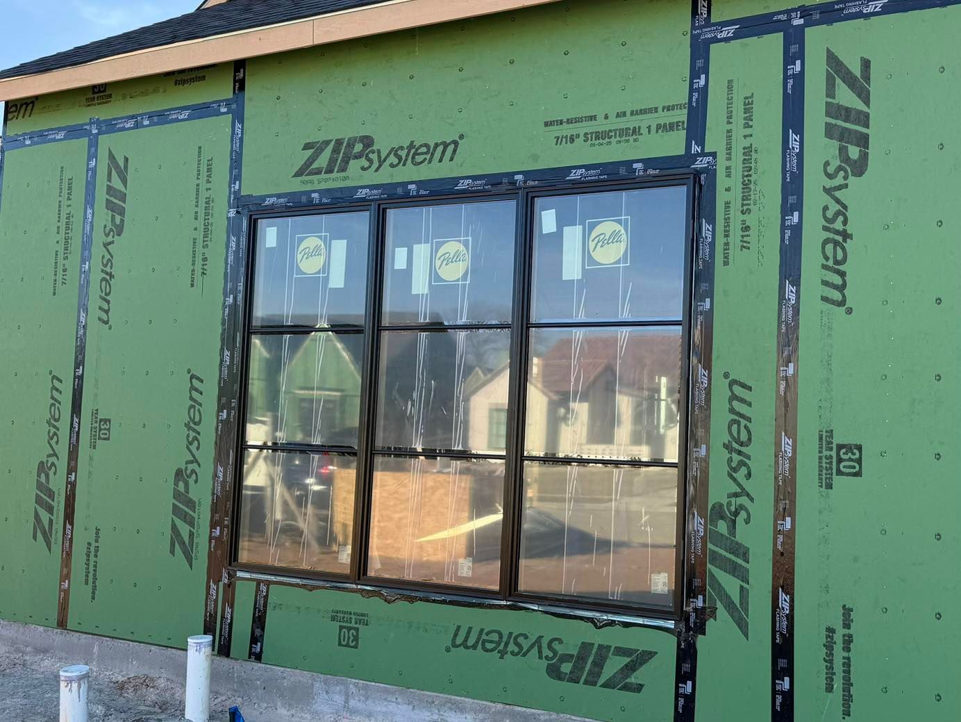 A house with a lot of windows is being built and is covered in zip system.