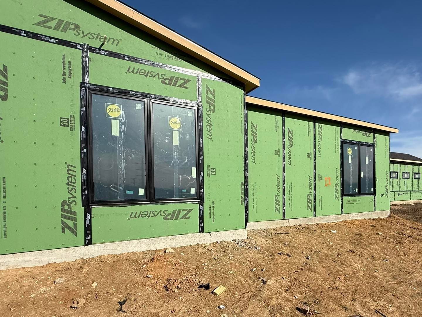 A house is being built with green siding and windows.
