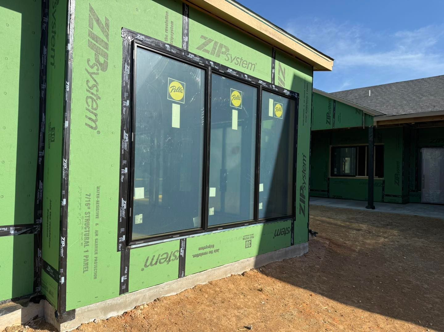 A house is being built with green siding and black windows.