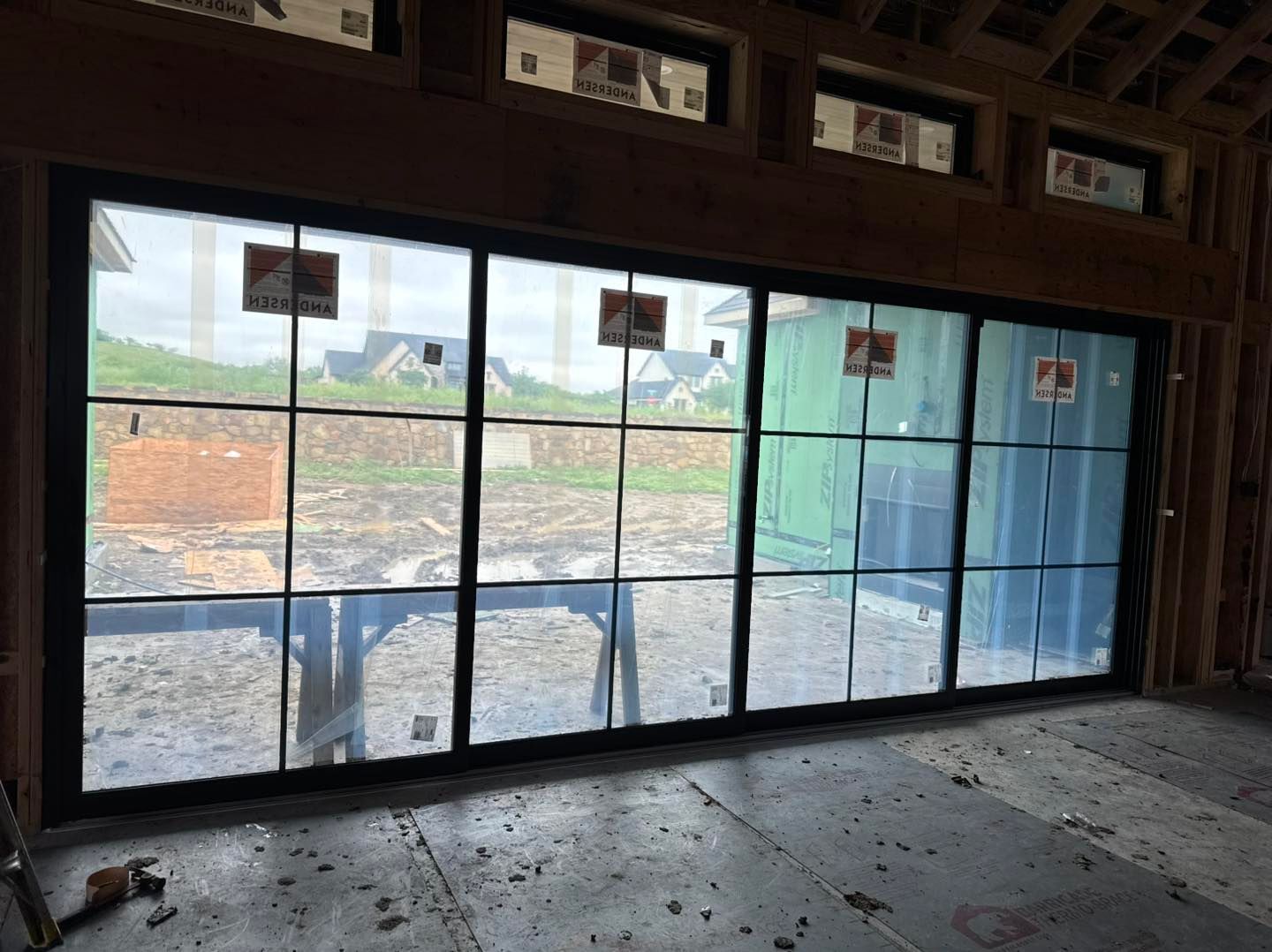 A room with a lot of windows and a green building in the background.