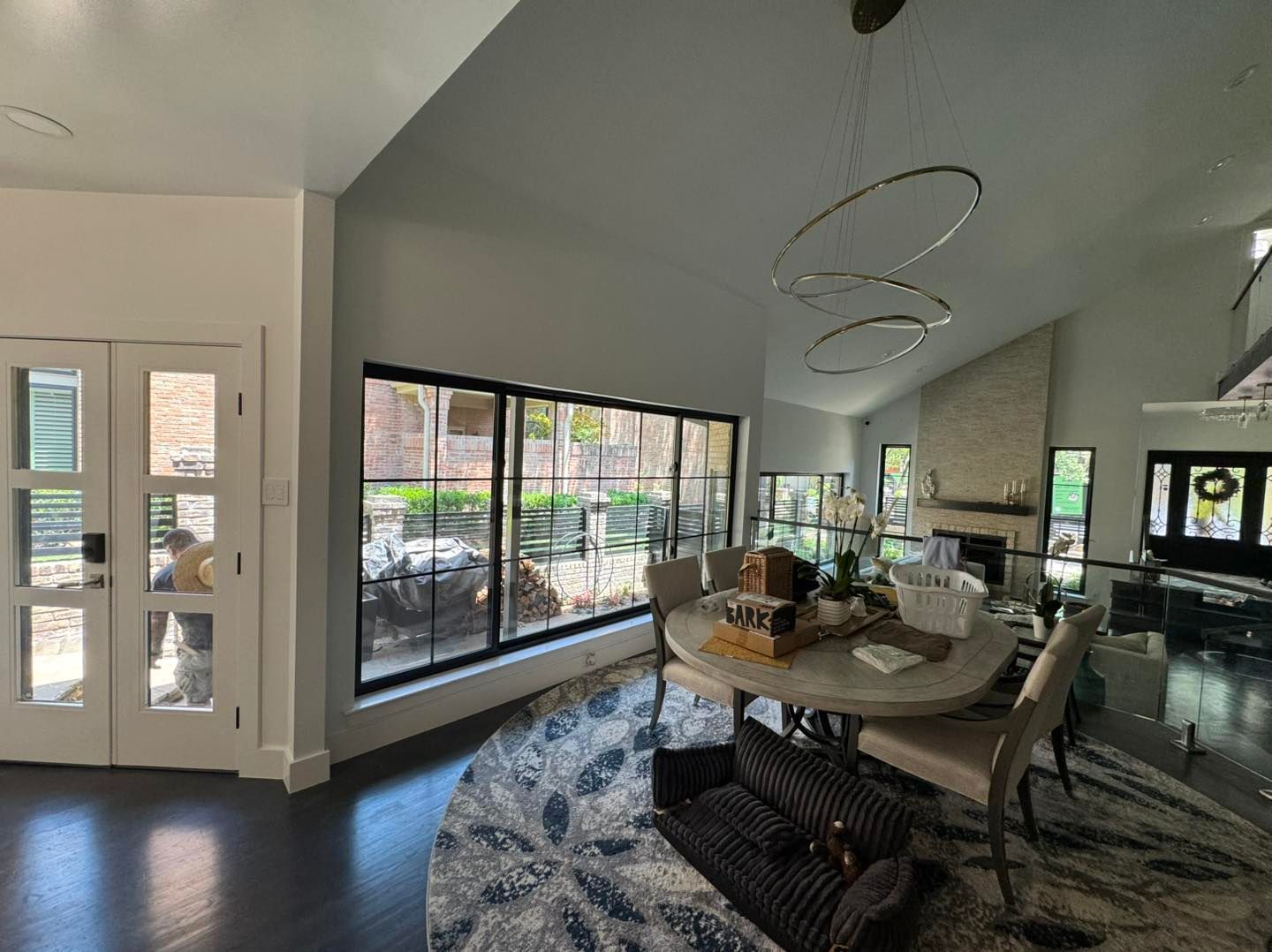 A living room with a dining table and chairs and a large window.