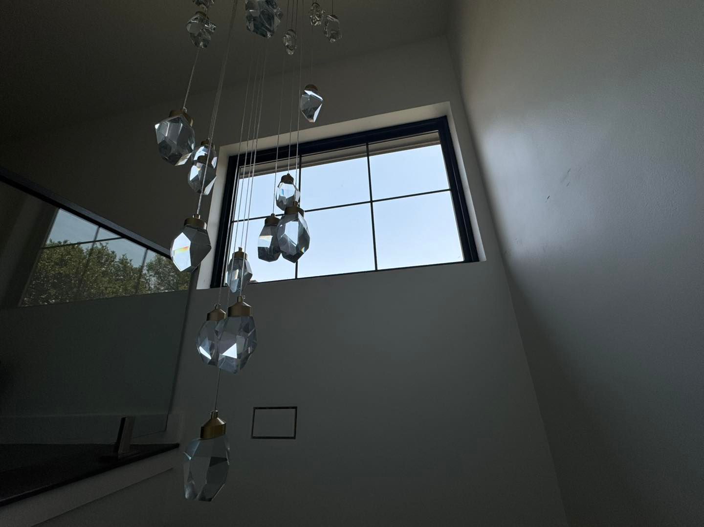 A chandelier is hanging from the ceiling in front of a window