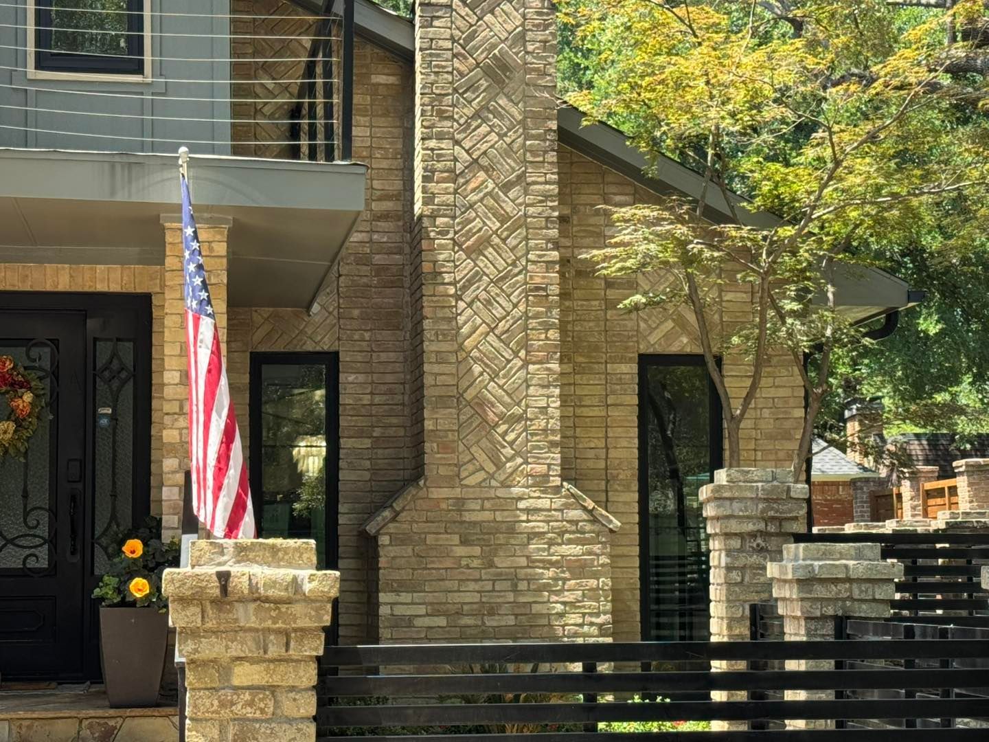 An american flag is flying in front of a brick house.