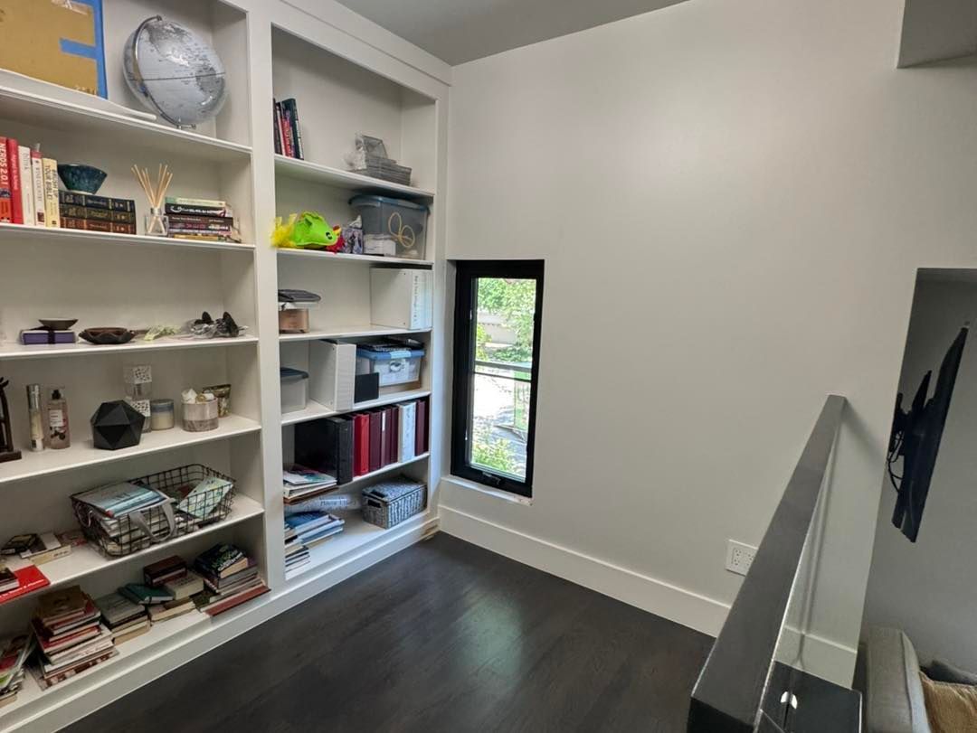 A room with a lot of shelves and a window.