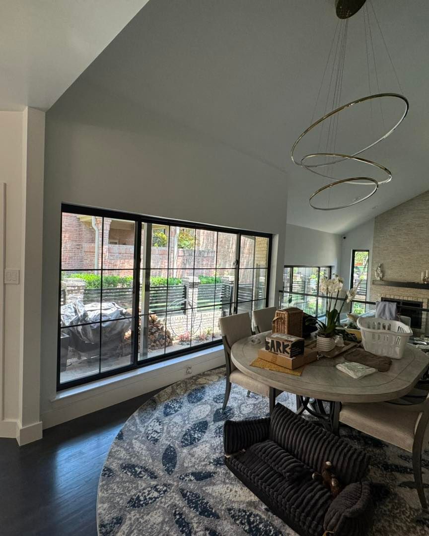 A living room with a table and chairs and a large window.