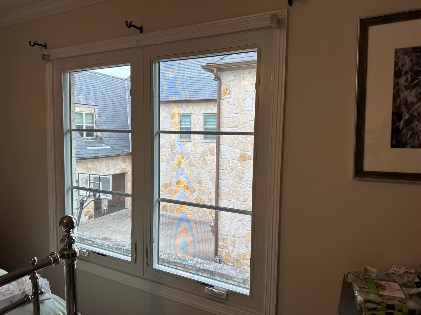 A bedroom with two windows and a picture on the wall.