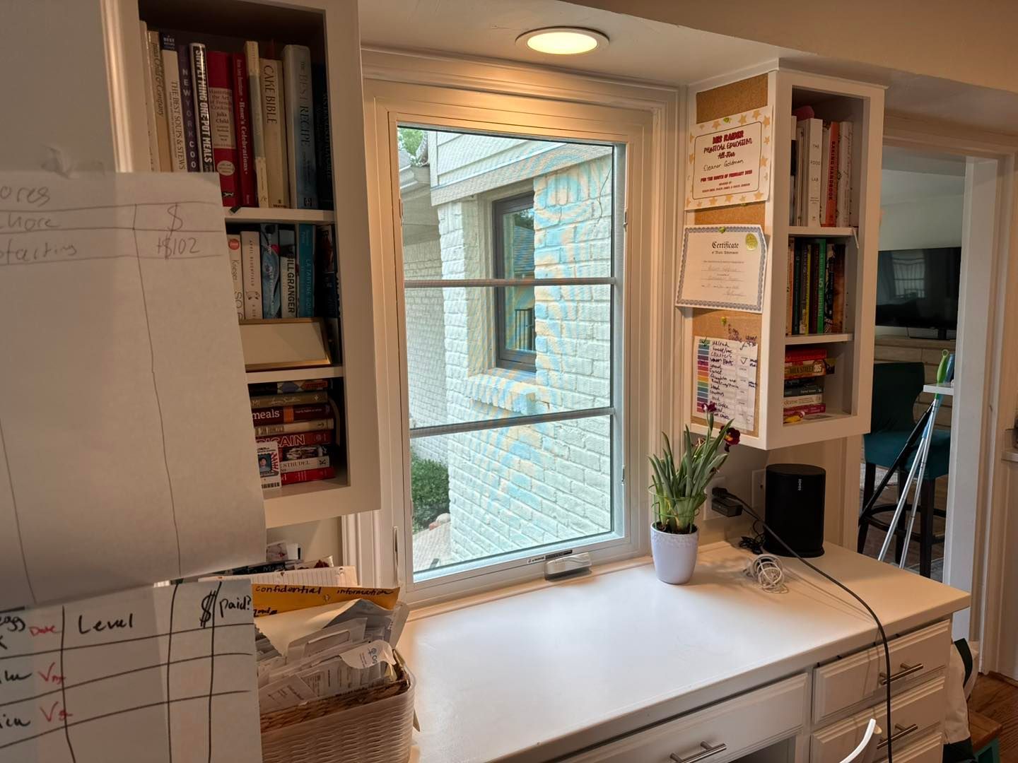 A desk with a potted plant on it in front of a window.